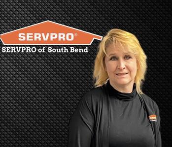 Woman smiling at camera with a black background and the SERVPRO logo to her right 
