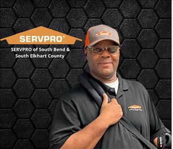 man looking at the camera while posing on a black background with an orange SERVPRO logo