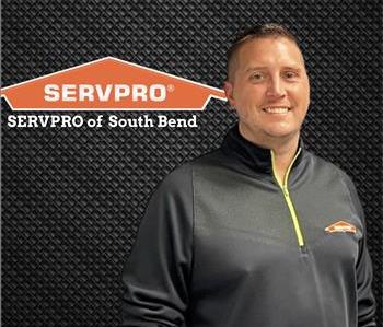 Image of a smiling man in a black shirt standing under a SERVPRO logo